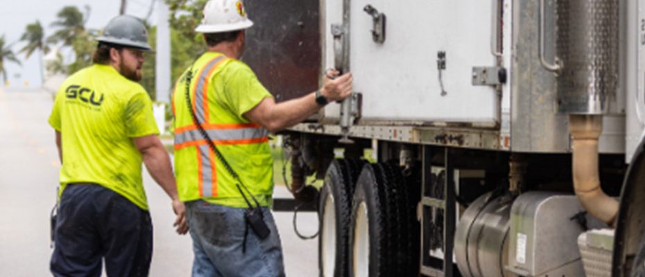 two workers on site next to a truck