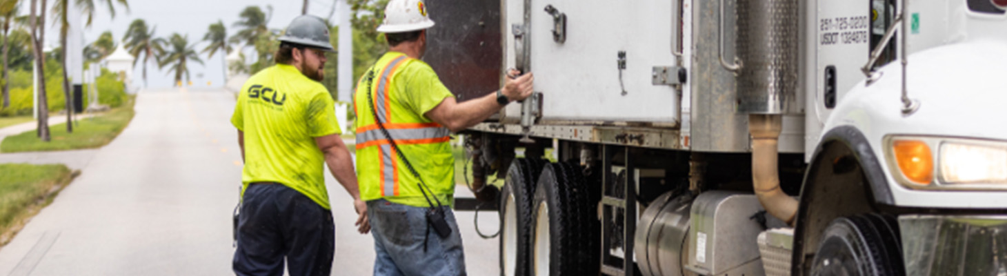 two workers on site next to a truck