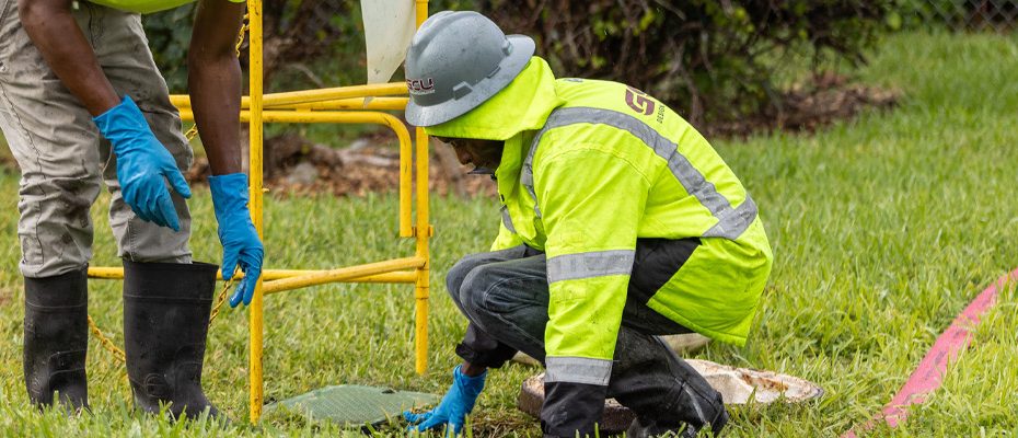 two workers inspecting a manhole